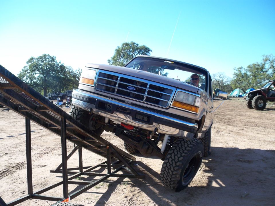 Lifted brown Ford Bronco on a metal ramp outdoors.