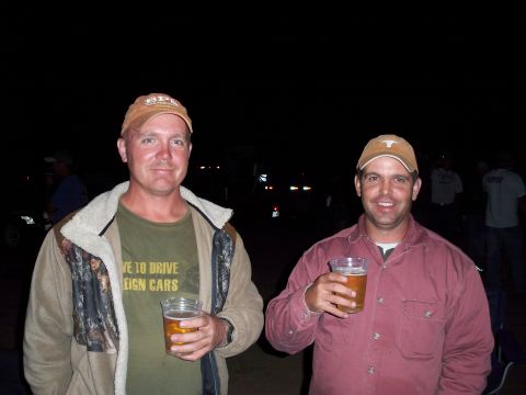 1996 Ford Bronco - Two men enjoy drinks at an outdoor event at night, with other people and vehicles visible in the background.