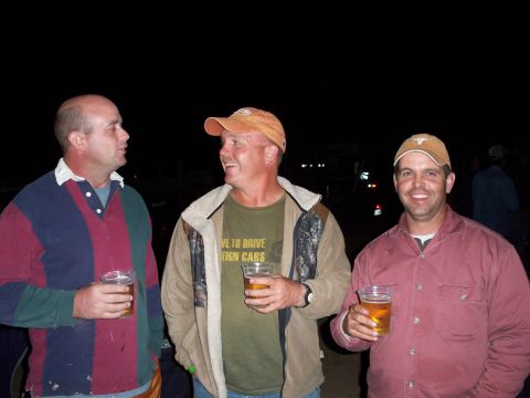 1996 Ford Bronco - Three men enjoy drinks outdoors at night, with one man's shirt displaying a message about driving foreign cars.