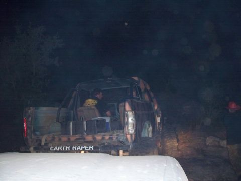 1996 Ford Bronco - A camouflaged off-road vehicle is parked at night, with people inside and gear in the back.
