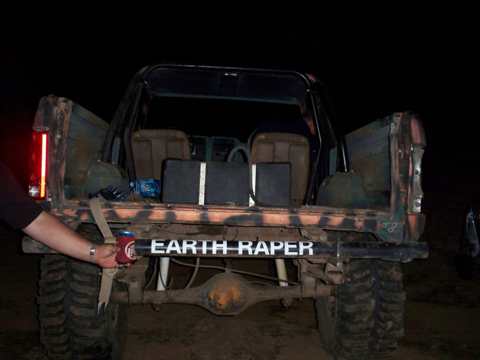 Rear view of a modified SUV with "EARTH RAPER" text on the bumper and camouflage paint