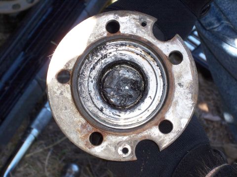 1996 Ford Bronco - A close-up view of a worn wheel hub assembly, showing a damaged bearing packed with old grease.