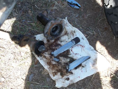 1996 Ford Bronco - Vehicle axle components, including shafts and a hub assembly, are laid out on a dirty rag on the ground.