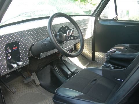 1985 Ford Bronco - Interior view shows custom diamond plate dash, aftermarket steering wheel, and racing seat with toggle switches.