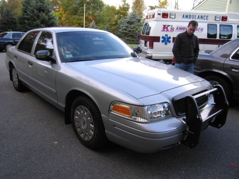2001 Ford Crown Victoria - This silver 2001 Ford Crown Victoria features a prominent push bar on its front end, seen parked on an asphalt surface.