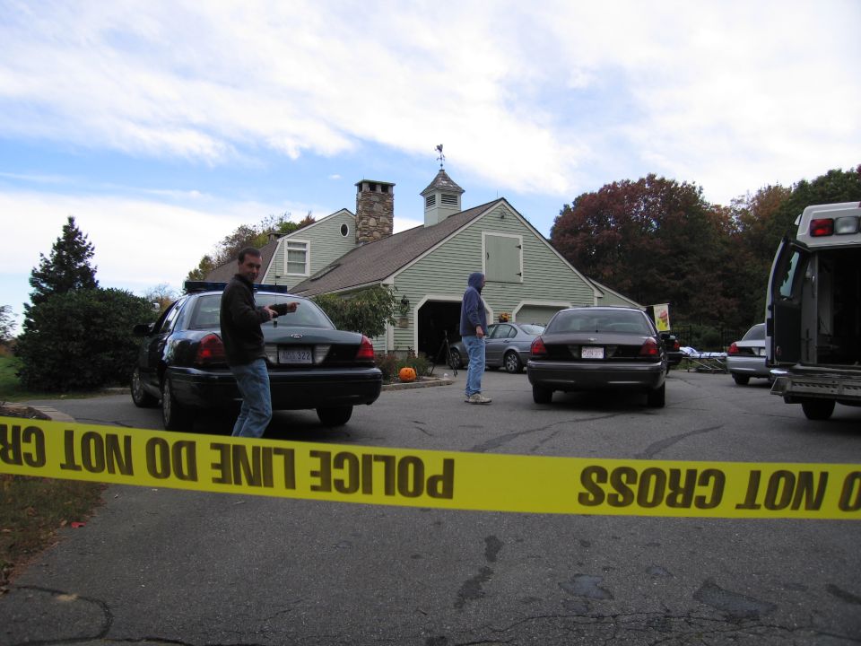 Rear view of a black 2001 Ford Crown Victoria police car behind yellow police tape