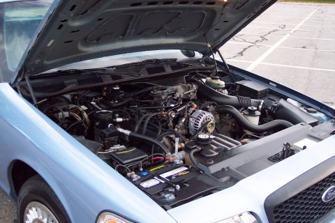 2001 Ford Crown Victoria - The engine compartment of a light blue 2001 Ford Crown Victoria is visible with the hood raised.