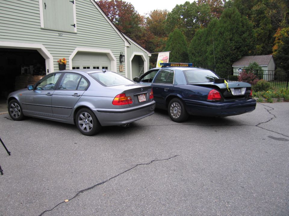 Dark blue police car parked next to a silver sedan in a driveway