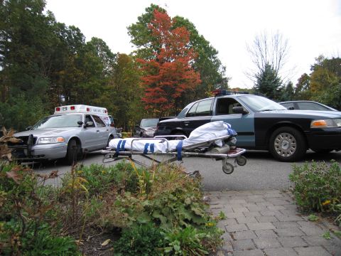 2001 Ford Crown Victoria - Emergency vehicles, including a police car and ambulance, are staged with a stretcher in a residential area.