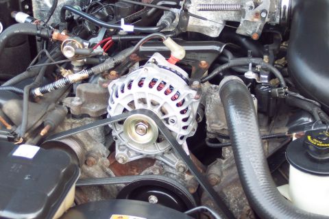 2001 Ford Crown Victoria - A close-up view of an engine bay focuses on the alternator and serpentine belt system.