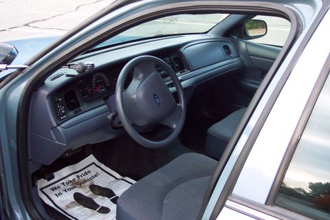 2001 Ford Crown Victoria - Interior view of a 2001 Ford Crown Victoria, likely a former police vehicle, with a branded floor mat.