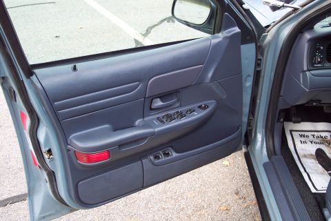 2001 Ford Crown Victoria - Interior view of a blue car's door panel and dashboard, showing power controls and a floor mat.