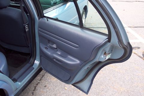 2001 Ford Crown Victoria - The interior door panel and rear seat of a 2001 Ford Crown Victoria are visible.