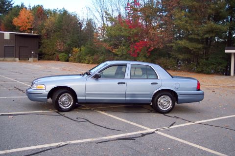 2001 Ford Crown Victoria - A light blue 2001 Ford Crown Victoria sedan is parked in an outdoor lot during autumn.