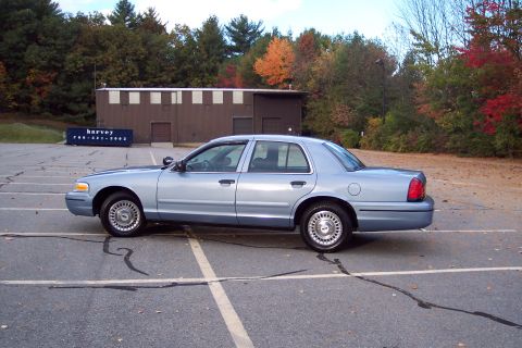 2001 Ford Crown Victoria - Side profile of a light blue 2001 Ford Crown Victoria sedan parked in an empty lot.