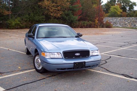 2001 Ford Crown Victoria - Front 3/4 view of a blue 2001 Ford Crown Victoria in a parking lot during autumn.