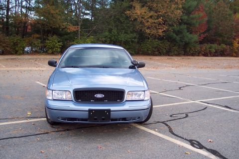 2001 Ford Crown Victoria - A blue 2001 Ford Crown Victoria is parked in an empty lot during autumn.