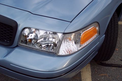 2001 Ford Crown Victoria - Front corner view of a light blue 2001 Ford Crown Victoria, highlighting the headlight and turn signal assembly.