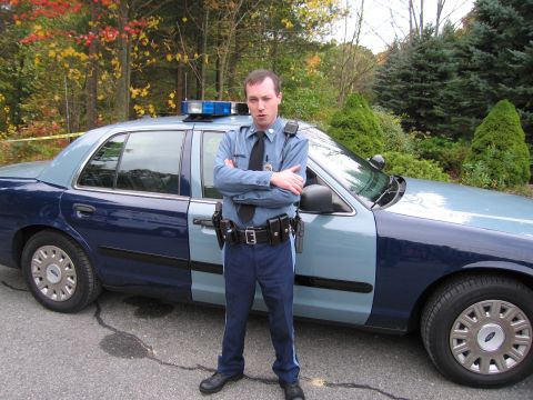 2001 Ford Crown Victoria - A police officer stands next to a two-tone Ford Crown Victoria patrol car, likely from the early 2000s.