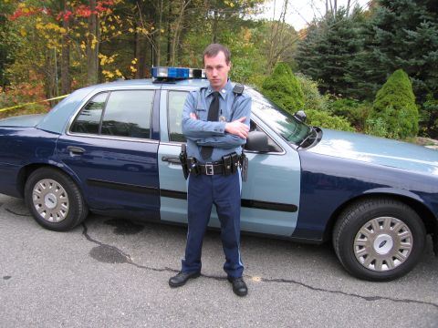 2001 Ford Crown Victoria - Officer stands in front of a two-tone Ford Crown Victoria police car.
