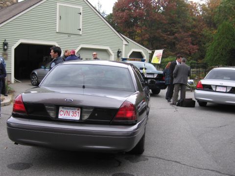 2001 Ford Crown Victoria - Three Ford Crown Victorias are parked outside a garage, with several people standing around.