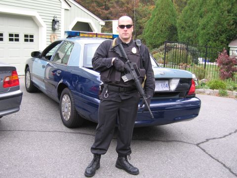 2001 Ford Crown Victoria - Officer stands by a 2001 Ford Crown Victoria police car. Another vehicle is partially visible on the left.