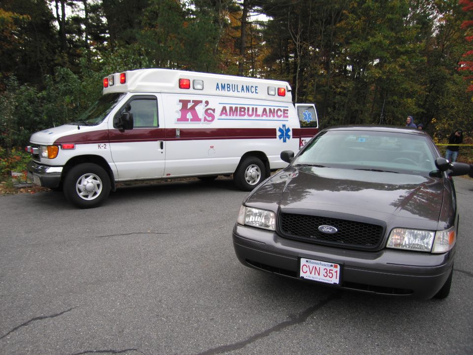 Dark gray 2001 Ford Crown Victoria parked next to a white K's Ambulance van