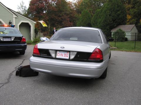 2001 Ford Crown Victoria - Two Ford Crown Victoria police cars are parked in a driveway, one silver and one dark blue.