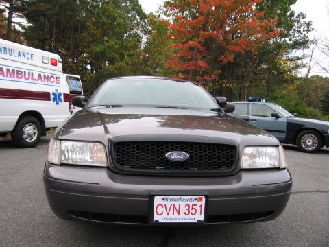 2001 Ford Crown Victoria - A dark gray Ford Crown Victoria is parked in front of an ambulance and a police car.