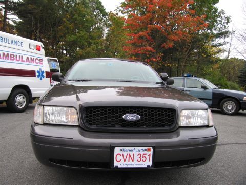 2001 Ford Crown Victoria - A dark gray 2001 Ford Crown Victoria is parked next to an ambulance and a police car.