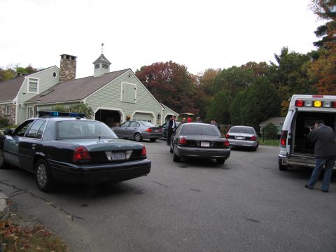 2001 Ford Crown Victoria - Multiple vehicles are parked on a street in front of a large house with a detached garage.