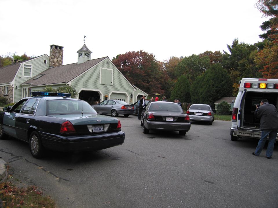 Dark police car, rear view, with blue lights on roof. License plate reads 'MDS 327'