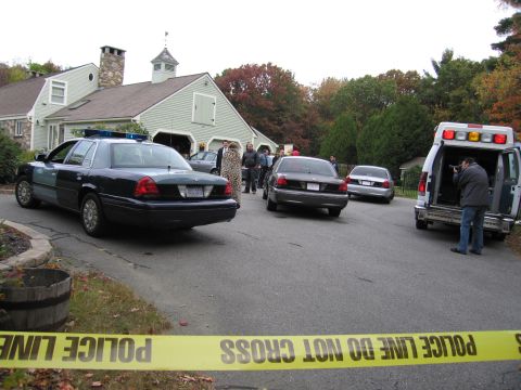 2001 Ford Crown Victoria - A police car is parked on a street, cordoned off with yellow police tape, with an ambulance and other vehicles visible in the background.