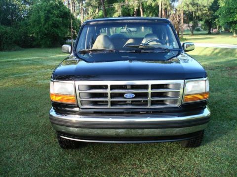 1994 Ford Bronco - Front view of a black Ford Bronco with a chrome grille and amber turn signals, parked on a grassy area.