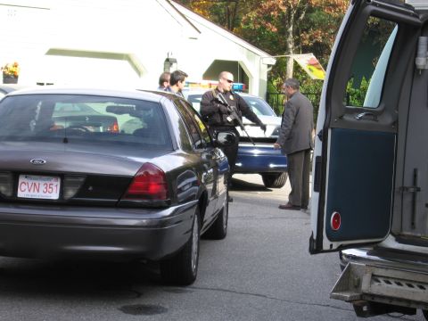 2001 Ford Crown Victoria - A police officer interacts with civilians near several parked vehicles, including a dark sedan and a police car.