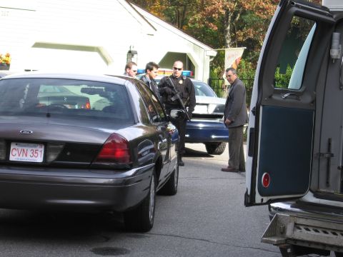 2001 Ford Crown Victoria - A dark gray 2001 Ford Crown Victoria is parked on a street with several people around it, including police officers.