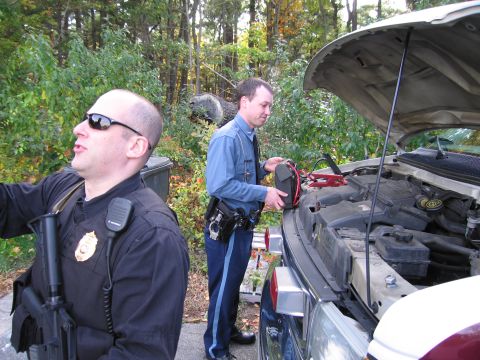2001 Ford Crown Victoria - Officers are attempting to jump-start a vehicle in a wooded area.