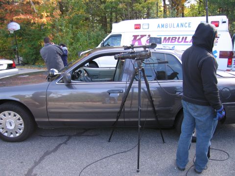 2001 Ford Crown Victoria - A video camera is set up next to a 2001 Ford Crown Victoria, with an ambulance visible in the background.