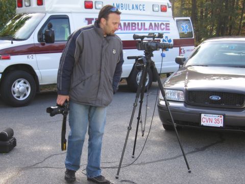 2001 Ford Crown Victoria - A 2001 Ford Crown Victoria is parked next to an ambulance, with a cameraman filming.