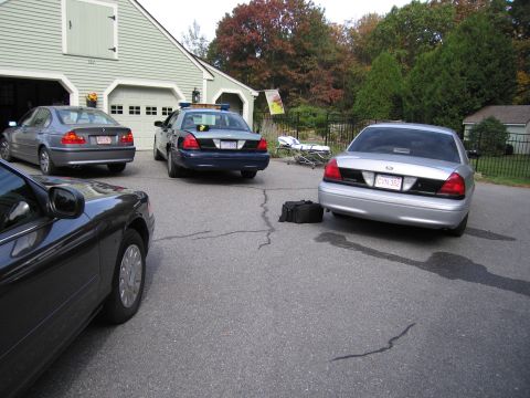 2001 Ford Crown Victoria - A silver 2001 Ford Crown Victoria is parked in a driveway with other vehicles, including a police car.