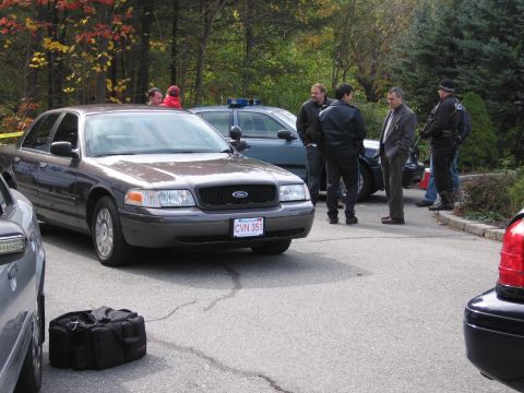 2001 Ford Crown Victoria - Several individuals, some in uniform, stand near a police car and other vehicles.
