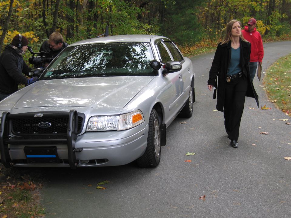 Silver Ford Crown Victoria police car with push bumper, parked on asphalt road