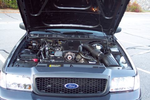 2001 Ford Crown Victoria - The engine bay of a Ford Crown Victoria is shown with the hood open, revealing the engine and other components.