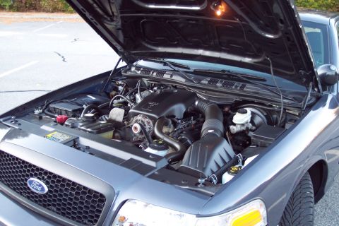 2001 Ford Crown Victoria - The engine bay of a 2001 Ford Crown Victoria is visible with the hood raised, revealing the V8 engine and other components.