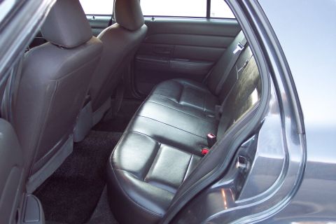 2001 Ford Crown Victoria - Interior view of the rear seating area of a 2001 Ford Crown Victoria, showing black leather seats and dark carpeting.