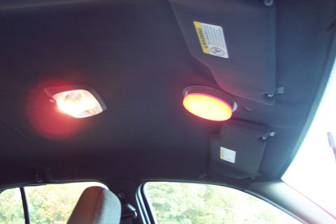 2001 Ford Crown Victoria - The interior of a vehicle shows two illuminated dome lights and a sun visor with a visible warning sticker.