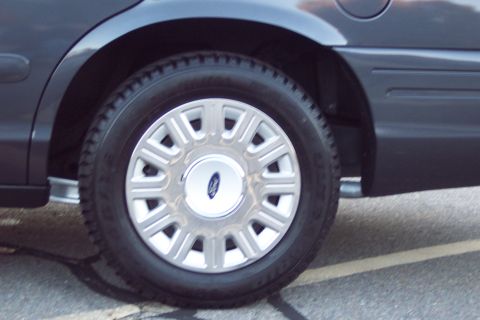2001 Ford Crown Victoria - Close-up of the rear wheel and fender of a Ford Crown Victoria, showing the distinctive hubcap.