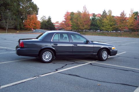 2001 Ford Crown Victoria - Side view of a 2001 Ford Crown Victoria sedan parked in a lot during autumn.