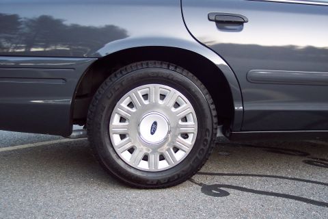 2001 Ford Crown Victoria - Close-up of the rear wheel and fender of a dark gray Ford Crown Victoria.