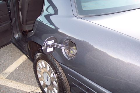 2001 Ford Crown Victoria - A close-up view of the fuel door and rear wheel of a dark gray Ford Crown Victoria.